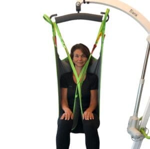 Woman in HumanCare High Basic Sling with lift; mobility support sling for home care use.