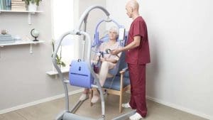 Arjo Maxi Twin Floor Lift safely transfers elderly woman from chair; ideal for home mobility support.
