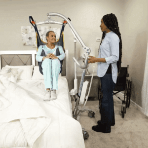 Handicare Carina350 EM/EE Floor Lift used for home care patient transfer, featuring caregiver assistance.