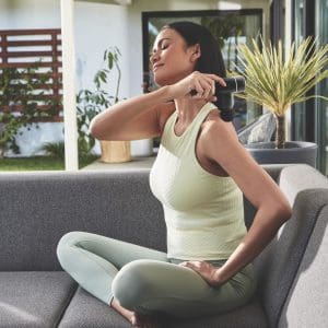 Woman uses HoMedics Percussion Massager for home shoulder pain relief and mobility support.
