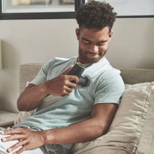 Man uses HoMedics Rebound Percussion Massager on upper arm for home muscle therapy.