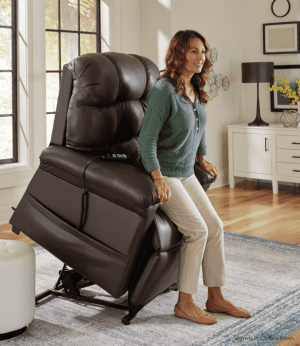 Brown leather lift recliner chair assists woman standing, ideal for home mobility support.
