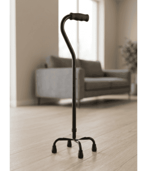 Black quad cane with four legs and curved handle for home mobility support.